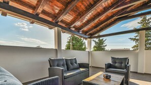 Un área de estar al aire libre techada, con muebles de mimbre y una mesa de madera.