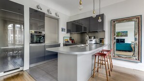 Une cuisine moderne dotée d’un îlot central, d’appareils électroménagers en acier inoxydable et d’un grand miroir.