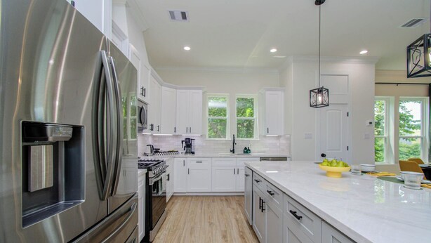 Una cocina moderna con armarios blancos, electrodomésticos de acero inoxidable y una isla grande con un cuenco de fruta.