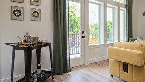 Una habitación con un sofá, una mesa con una botella y vasos, y cuatro objetos enmarcados en la pared.
