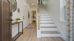 Una escalera con escalones de madera y paredes blancas, que sube a un piso superior.