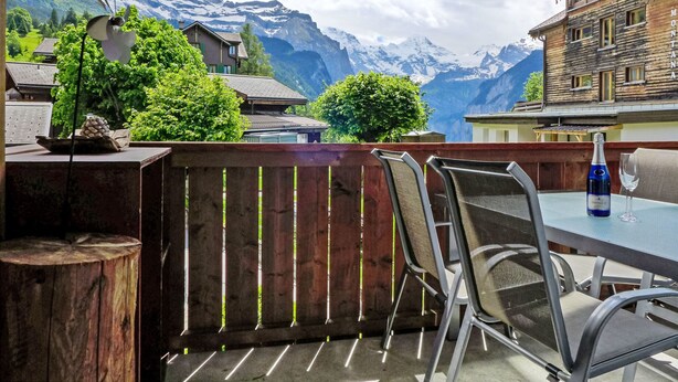 Una terraza con mesa y sillas con vistas a un paisaje montañoso.