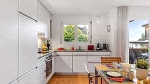Una cocina moderna con armarios blancos, una mesa de comedor de madera y una alfombra roja.