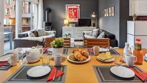 Una sala de estar moderna con comedor, que cuenta con una chimenea, un televisor y un ventanal con vistas a un paisaje urbano.
