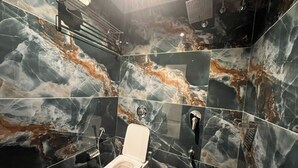 A modern bathroom with a marble backsplash and a toilet. - Hotel Grand Executive  (Mumbai)