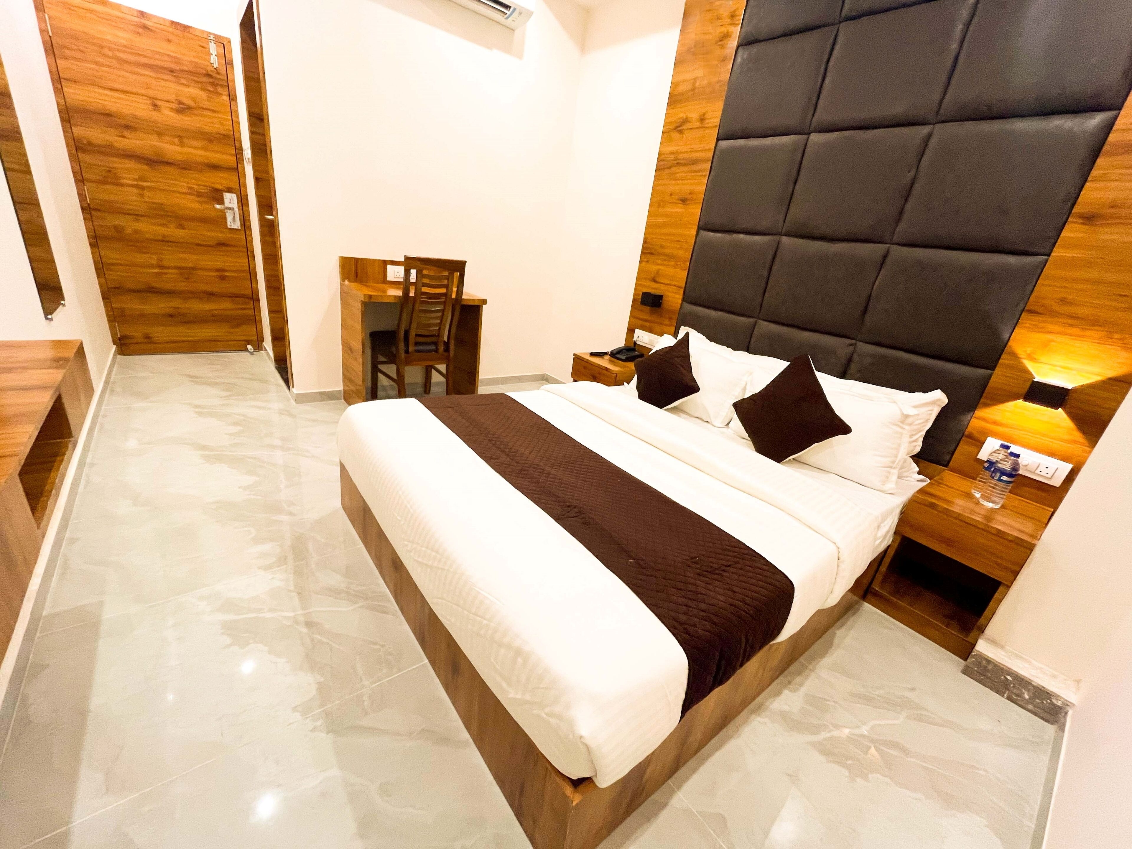 Une chambre d’hôtel moderne avec un grand lit, un bureau en bois et une chaise.