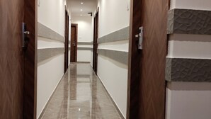 A hallway with wooden doors, a marble floor, and recessed lighting. - Hotel Grand Executive  (Mumbai)