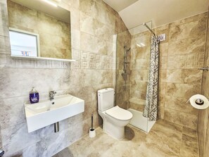 Een badkamer met een wit wastafel, toilet en douche.