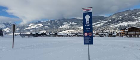 A snow-covered landscape with a sign indicating the start of a ski trail to Brixen, 4.2 km away.