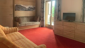 A room with a sofa, a television on a wooden cabinet, a painting on the wall, and a red carpet. - Appartements Robert Bechlwirt (Kirchberg in Tirol)