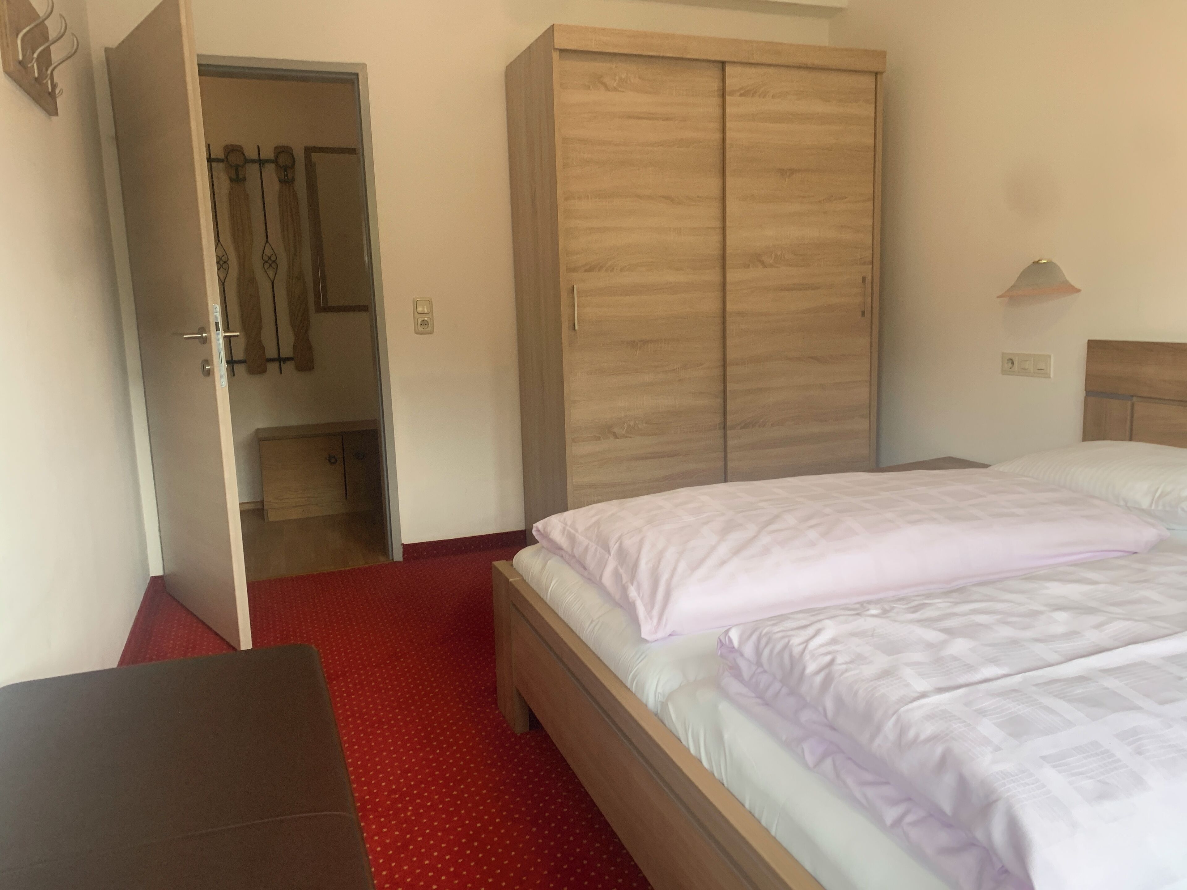 A hotel room with a bed, a wardrobe, and a bench.