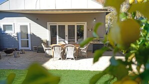 Una casa con un patio, muebles de exterior y una parrilla.