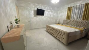 A bedroom with a bed, a TV mounted on the wall, and a ceiling fan.