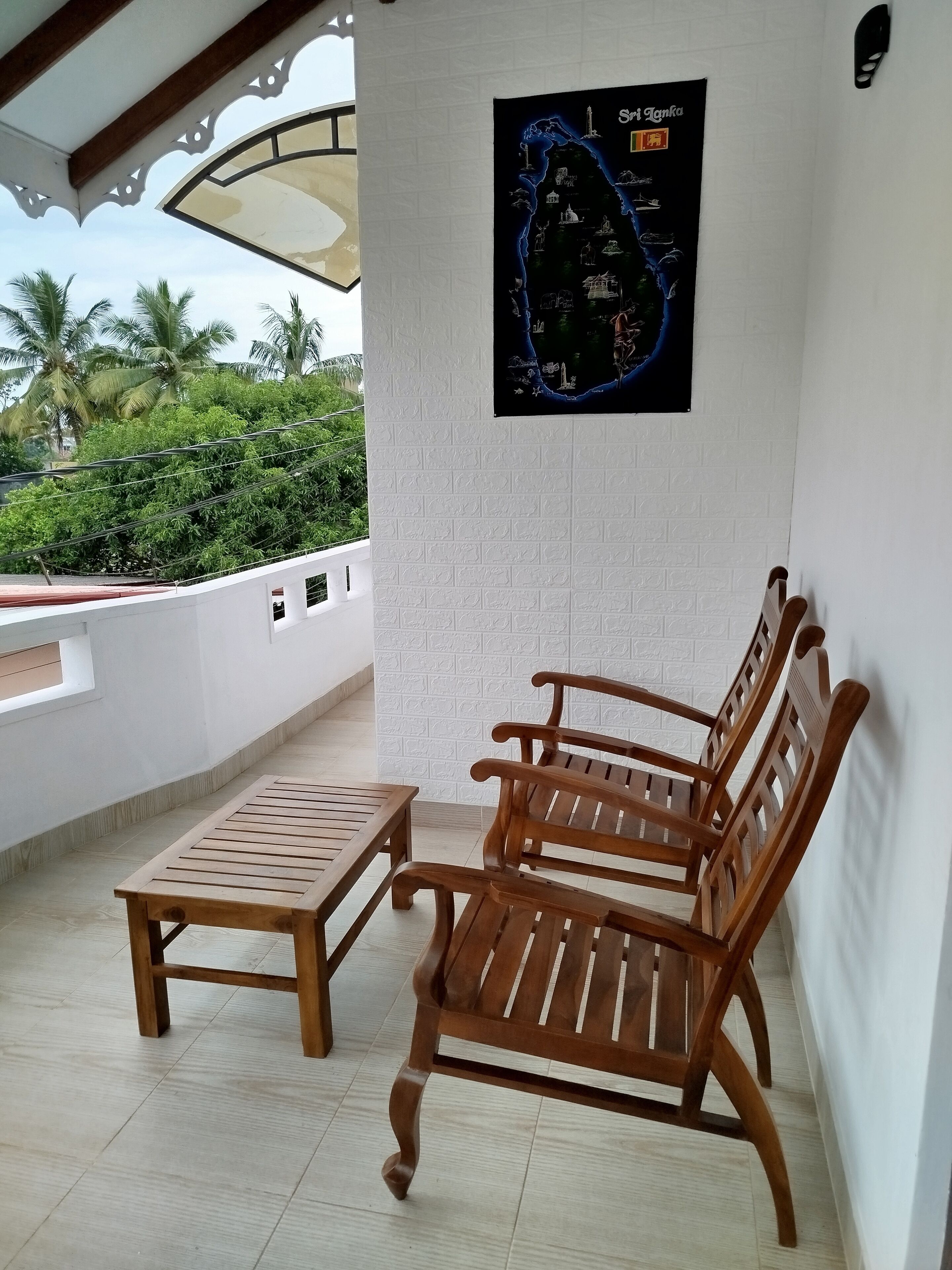 A wooden bench and table on a balcony with a white textured wall and a map poster.