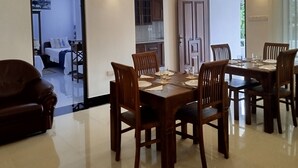 A spacious dining area with a large wooden table and chairs, a ceiling fan, and pendant lighting. - Cosy White Palace  (Negombo)