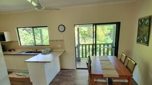 Une cuisine spacieuse avec un coin repas, un plancher en bois et une vue sur la verdure grâce à de grandes fenêtres.