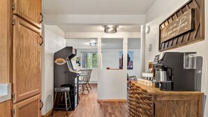 Eine Küche mit Holztresen, Barhocker, einer Kaffeemaschine und einem Schild an der Wand.