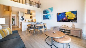 A modern living room with a dining area, a kitchen, and a staircase leading to an upper level. - Top Floor, 360 deg Ocean View, Totally Remodeled, 2-bed 2 bath with split AC (Kihei)