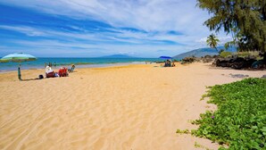 A beach with people relaxing under umbrellas, a clear sky, and a mountain in the background. - Top Floor, 360 deg Ocean View, Totally Remodeled, 2-bed 2 bath with split AC (Kihei)