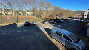 A parking lot with several cars and a van, surrounded by trees and buildings. - Apartment t2 floor at the edge of the lot (Espalion)