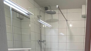 A modern bathroom with a white sink, mirror, and shower. - Apartment t2 floor at the edge of the lot (Espalion)