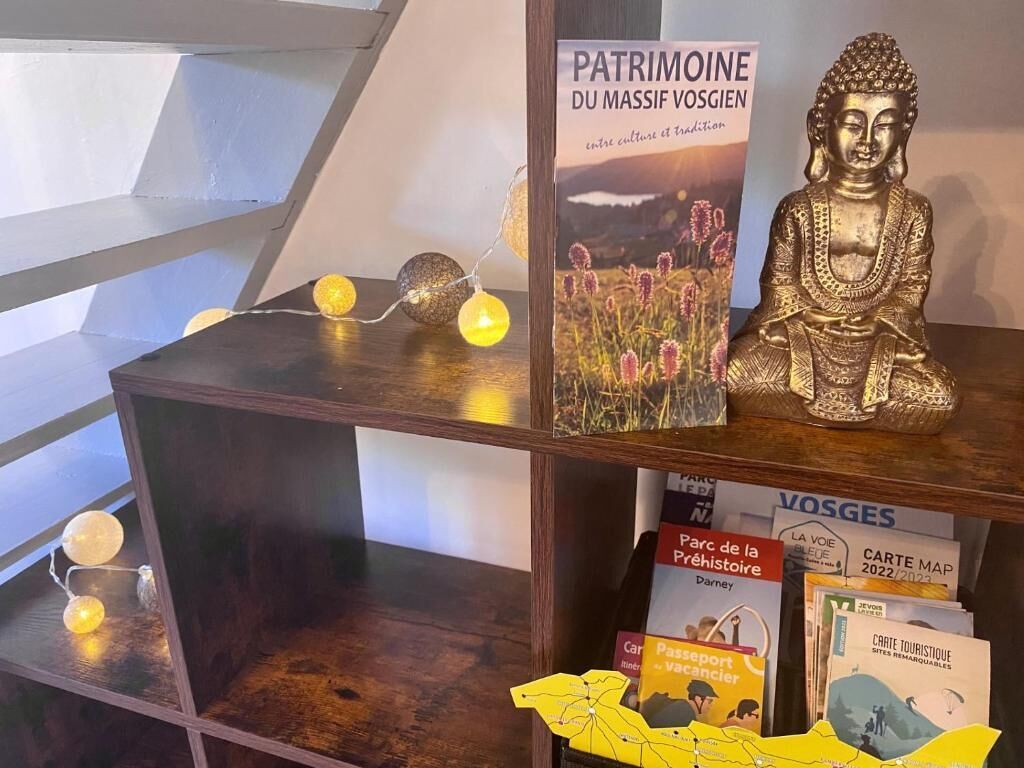 En utställning med en Buddha-staty, en bok med titeln ”Patrimoine du Massif Vosgien” och turistbroschyrer.