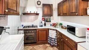 A kitchen with wooden cabinets, a stove, oven, microwave, and a sink.
