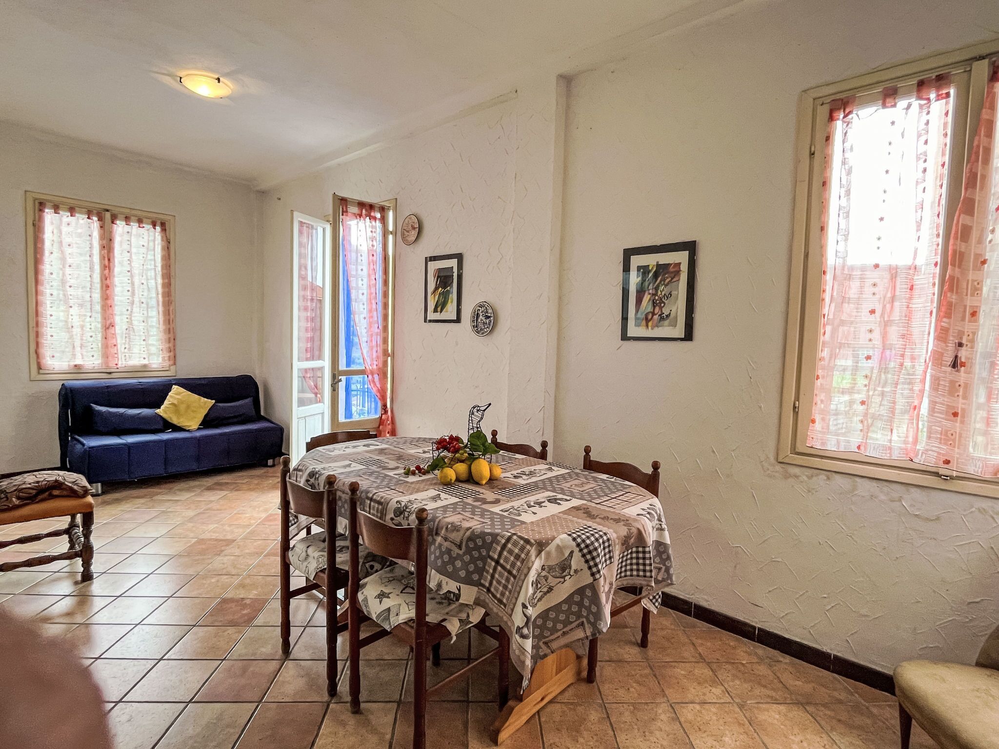 A dining area with a table set for four, a blue sofa, and a door leading outside.