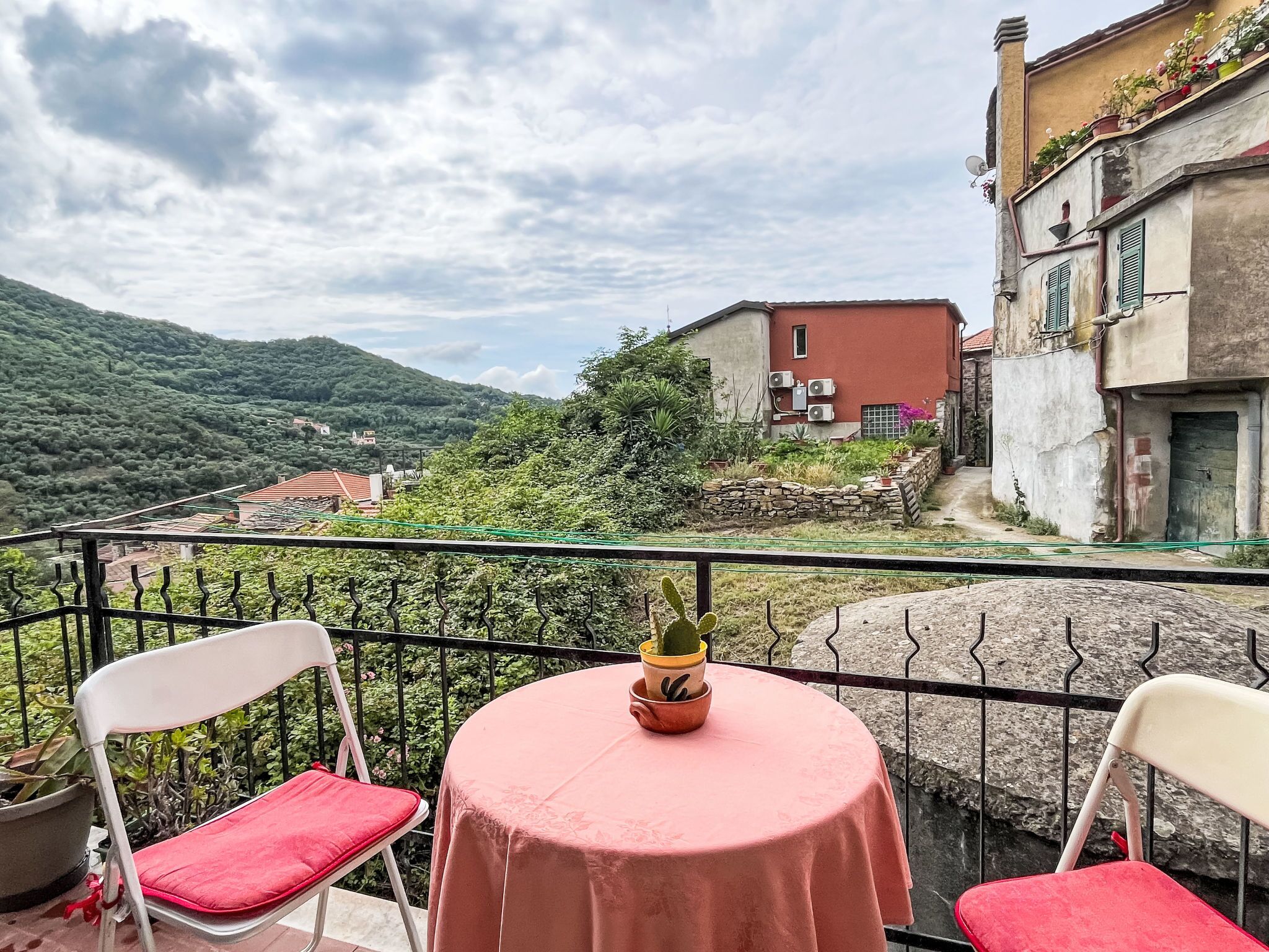 Un balcon avec deux chaises et une table, offrant une vue sur un paysage montagneux et un village.