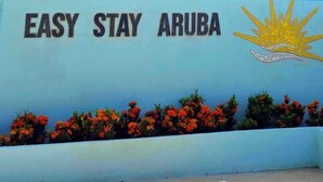 A wall with the text "EASY STAY ARUBA" and a sun emblem.