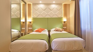 Quarto de hotel com duas camas, um espelho grande e um padrão geométrico na parede.