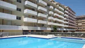 A swimming pool with a metal railing, surrounded by a multi-story building with balconies. - Apartment in Caorle near Sea Beach & Pool (Caorle (VE))
