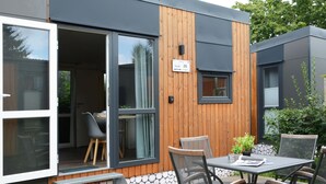 Une terrasse extérieure moderne, dotée d’une table et de chaises, d’une terrasse en bois et d’un mur en pierre.