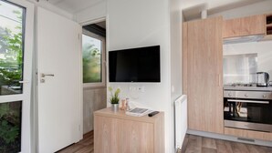 Une cuisine moderne équipée d’un four encastré, d’une cuisinière et d’un four à micro-ondes. On y trouve un meuble en bois sur lequel est fixé un téléviseur à écran plat.