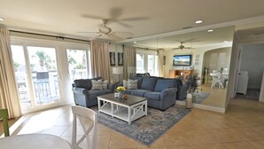 Ein geräumiges Wohnzimmer mit grauem Sofa, weißem Couchtisch und Deckenventilator.