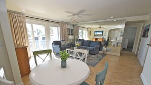 Ein geräumiges Wohnzimmer mit einem weißen runden Tisch, zwei Sofas und einem Deckenventilator.