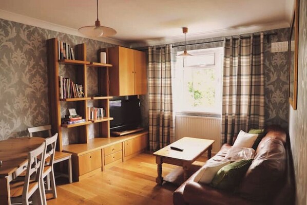 Relax in this inviting living room with a sofa, coffee table, TV, and bookshelf.