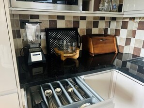 Kitchen area with coffee maker, utensil stand, and storage.