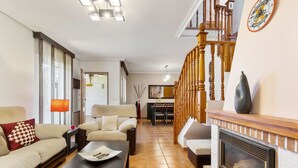 Un vaste salon doté d’une cheminée, d’un escalier et d’un coin repas.