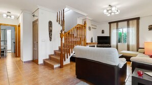 Un salon avec un escalier, un canapé, un téléviseur et une fenêtre avec des rideaux.