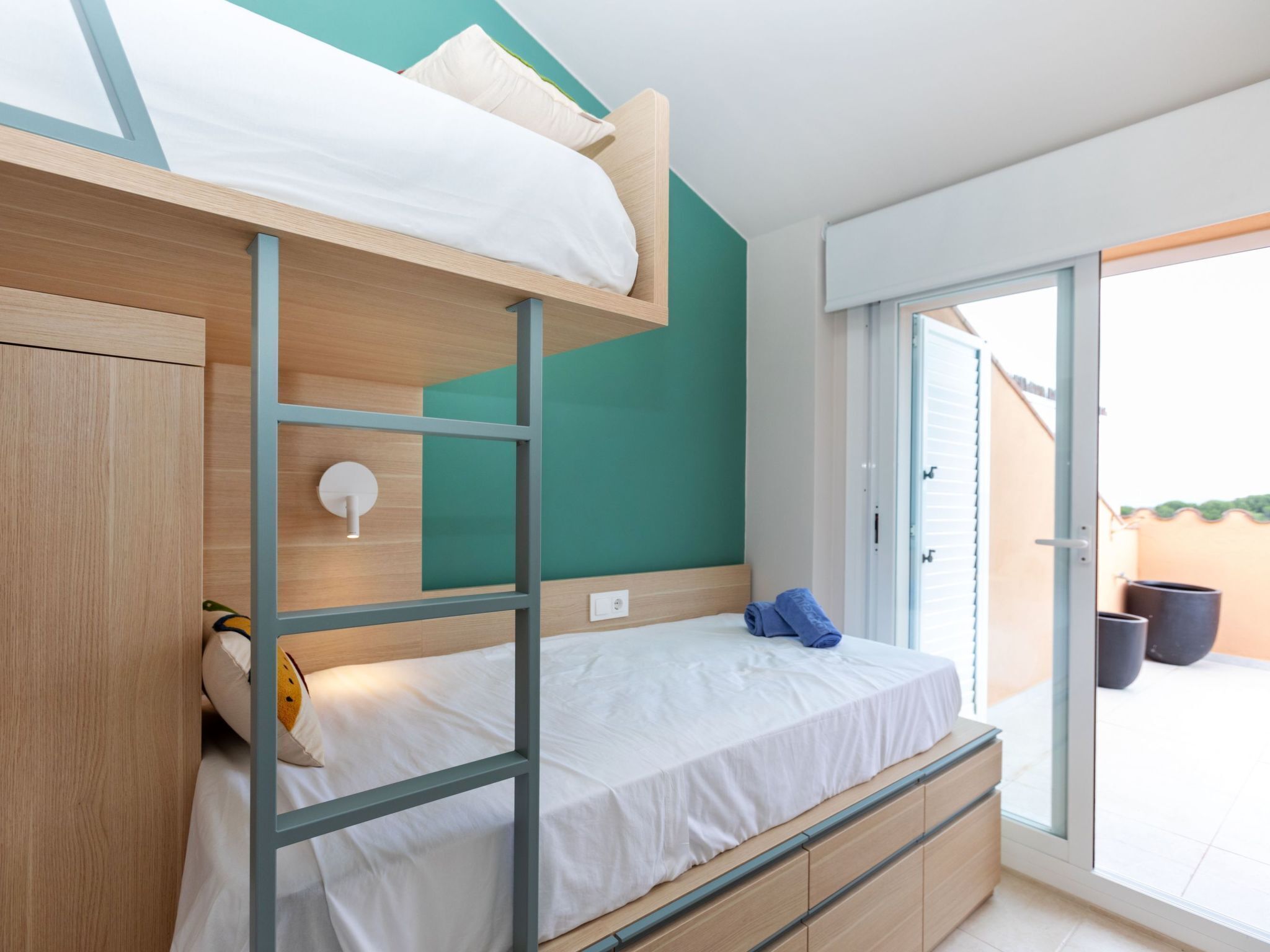 A bunk bed room with a wooden headboard, a white mattress, and a blue towel on the lower bunk.