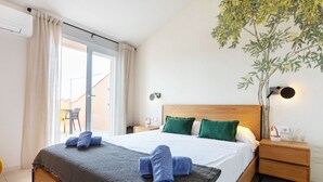 Ein Hotelzimmer mit einem großen Bett, einem Nachttisch, einer Wandlampe und Blick ins Freie.