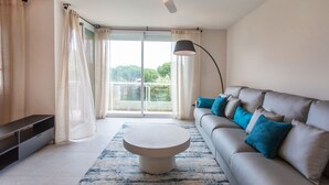 Ein modernes Wohnzimmer mit einem grauen Sofa, einem runden Couchtisch und einem Deckenventilator.