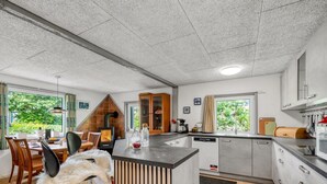 Une cuisine moderne dotée d’un îlot central, d’un coin repas offrant une vue agréable et d’un espace salon confortable avec un fauteuil en fourrure.