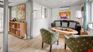 Un salon moderne avec un canapé, des fauteuils, une table basse et des œuvres d’art accrochées aux murs.