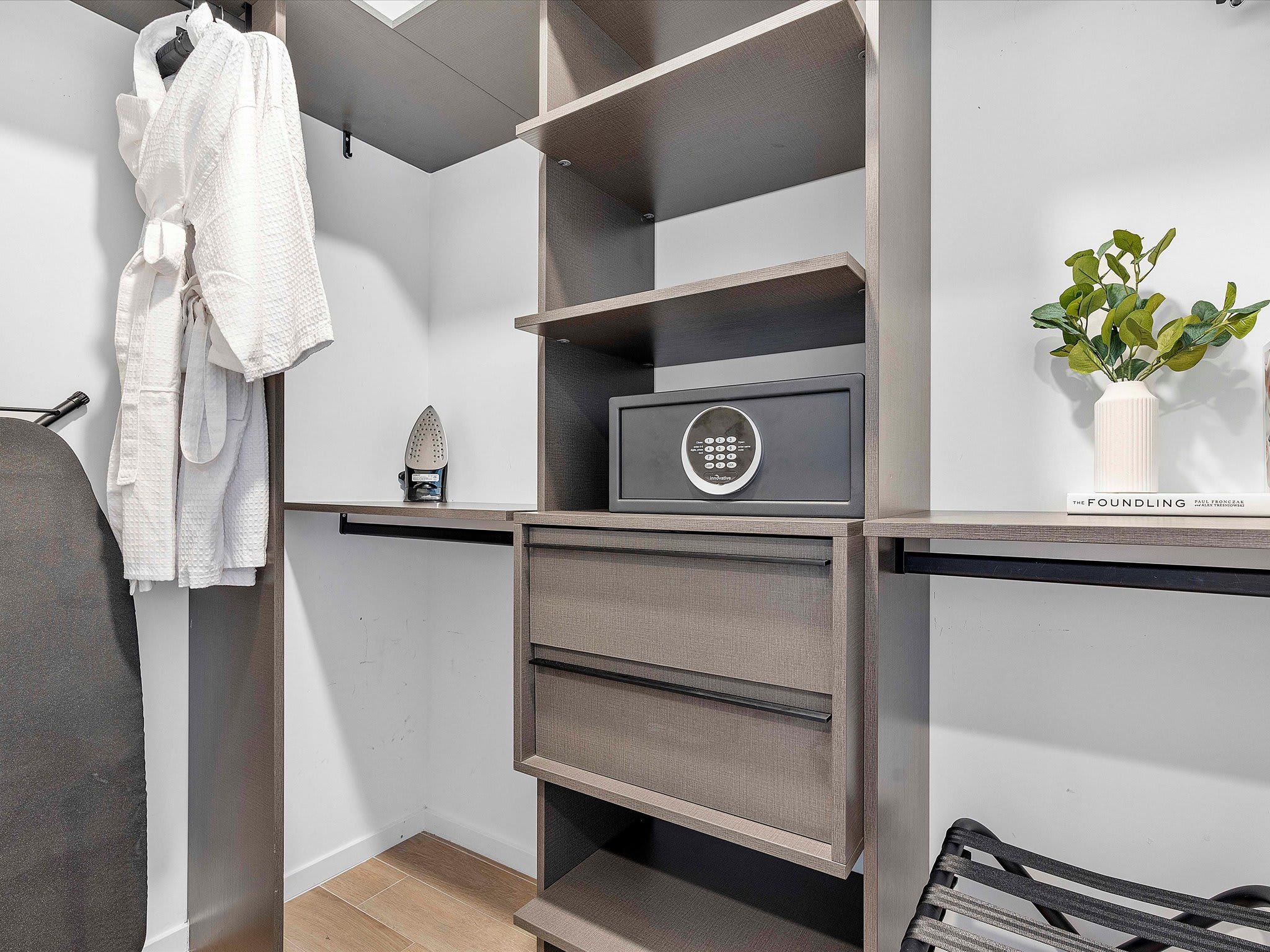 A modern bathroom with a built-in vanity, a towel rack, a small plant, and a book titled 'The Foundling'.