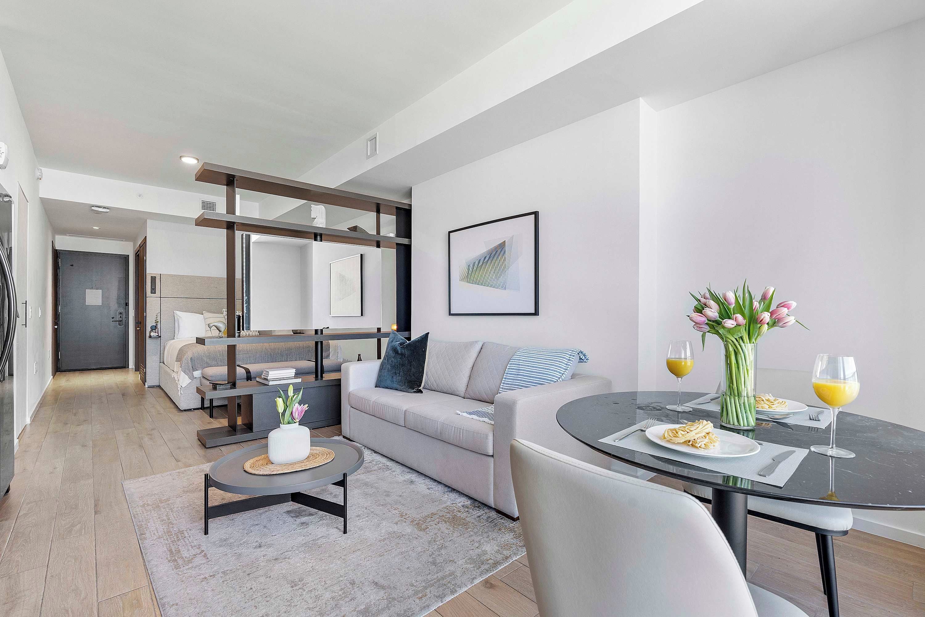 A modern living room with a sofa, coffee table, and dining table set for two.