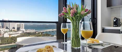 A dining table with a plate of pasta, two glasses of orange juice, and a vase of tulips.