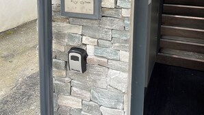 A keypad with a plaque above it, a doorbell, and a staircase in the background.