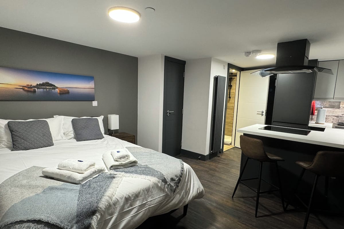 Habitación de hotel con cama, escritorio y vista a un atardecer sobre el agua.